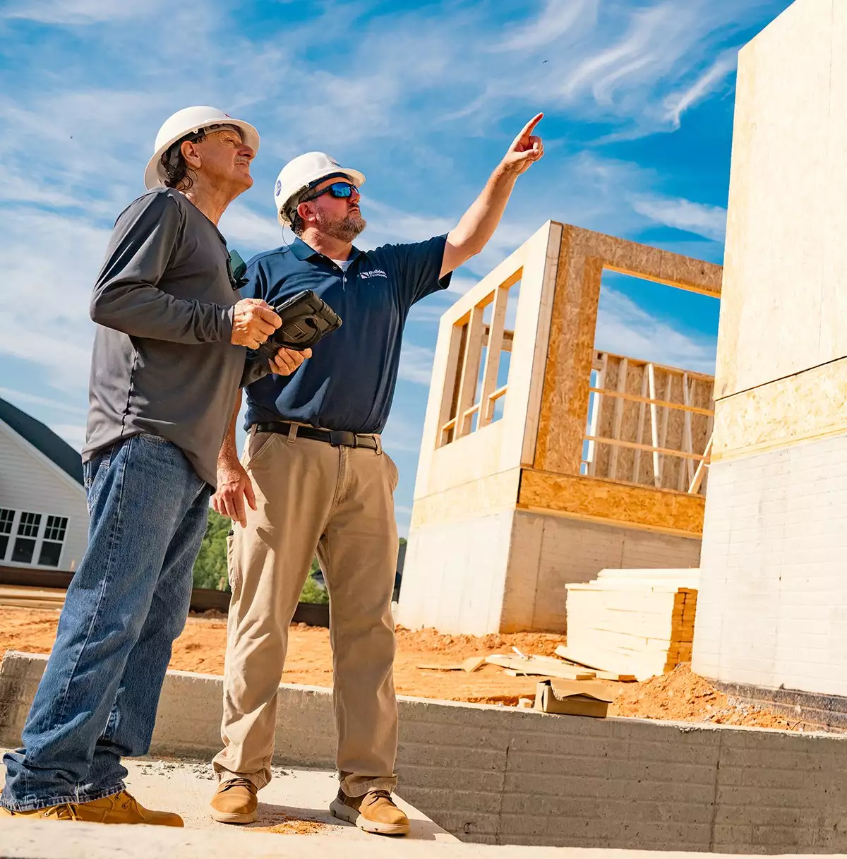 Builders in Conversation in Front of Houses Under Construction