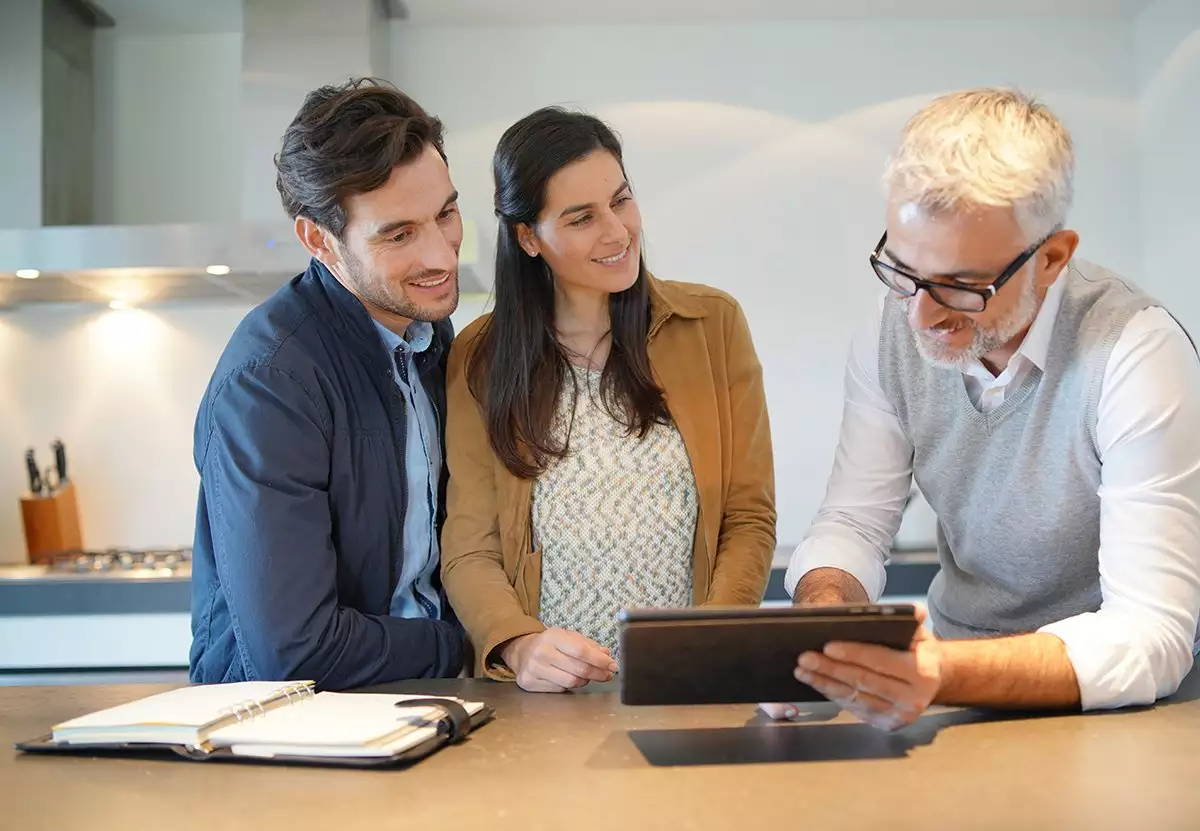 Specialist and Couple in a Kitchen Looking at a Tablet